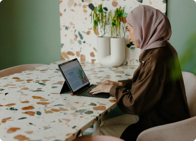 Businesswoman in hijab planning strategy on a tablet in a cozy workspace